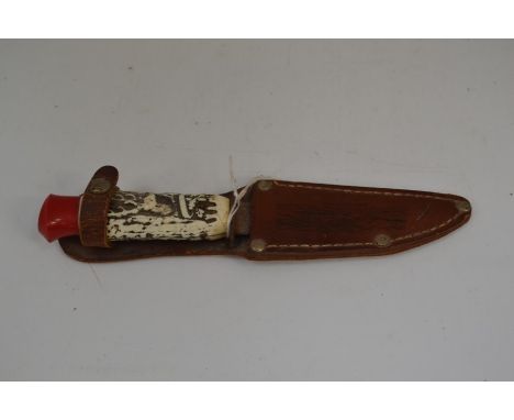 A circa 1960's camping knife with a 9cm blade complete with leather scabbard marked "Lulworth Cove". Plastic grips.&nbsp;