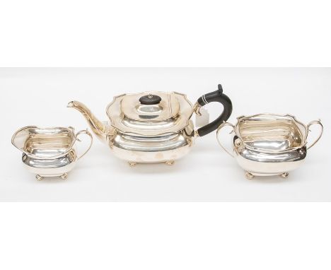 A George V silver three piece tea set, plain bodies with wavy rim on four stud feet, the teapot with ebony C-scroll handle an