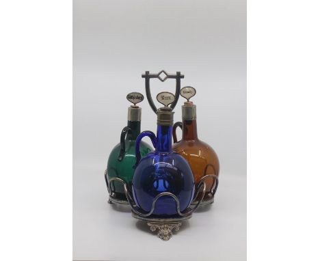 A late Victorian coloured glass decanter set and stand, comprising three bottle decanters with loop handles in green, blue an