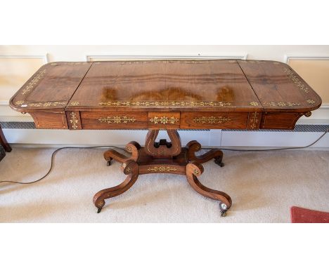 A Regency rosewood and brass inlaid sofa table, early 19th Century, the two rounded drop leaves above two small drawers on a 