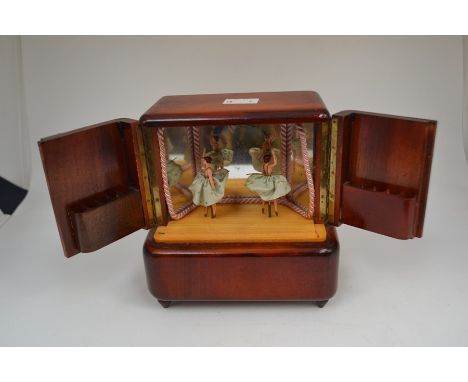 A 1930's wooden musical ballerina, cigarette dispenser, with a pair of dancing ballerina dolls, to the mirrored interior and 