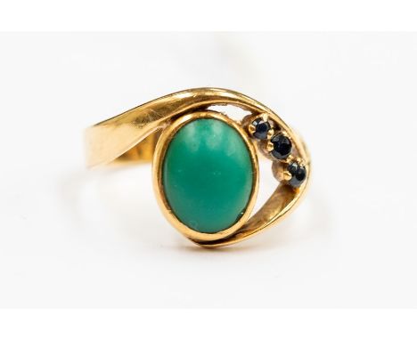 An 18ct gold ladies dress ring, comprising a cabochon oval cut  turquoise, rub-over set with three round cut sapphire claw se