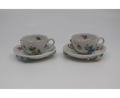 A pair of Dresden porcelain miniature teacups and saucers, late 19th Century, painted and applied with flowers and foliage, s