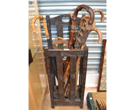 A late 19th Century carved stick stand, together with a collection of assorted walking sticks; one with a silver band and ins