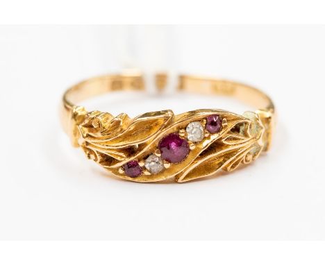 A late Victorian ruby and diamond 18ct gold ring, a curved row of alternate diamonds and rubies within a leaf and scroll deco