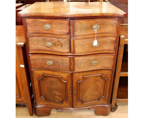 A George III and later serpentine fronted commode, the upper half with two doors with faux drawer fronts enclosing a single c