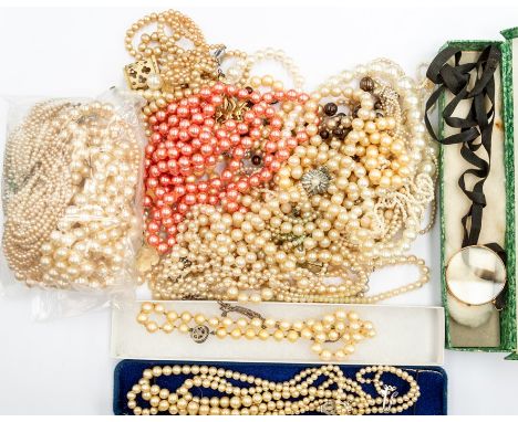 A collection of vintage faux pearl necklaces including graduated and regular strung versions, along with carved brooches and 