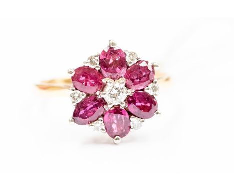 A ruby and diamond flower 18ct gold  cluster ring, comprising a central brilliant cut diamond with a surround of oval cut rub