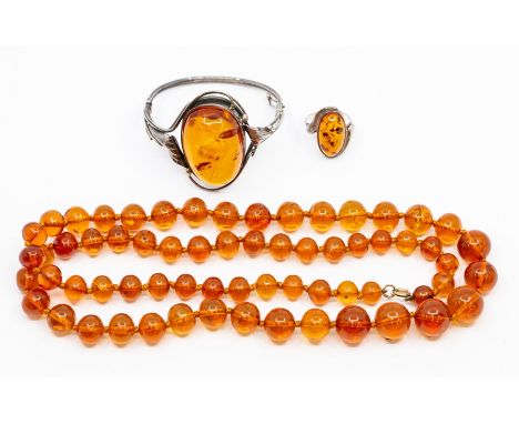 A collection of Amber to include an amber and white metal bangle, oval amber approx. 38mm x 27mm arts and crafts style surrou