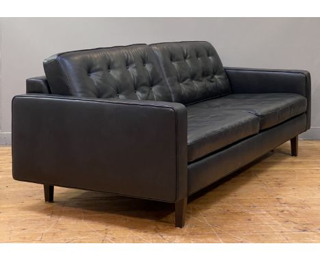 Heals, a contemporary sofa, upholstered in buttoned semi-aniline black leather and standing on ebonised square tapered suppor