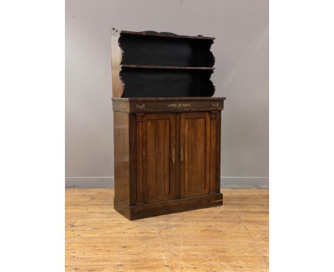 A Regency rosewood chiffonier, the raised back with two open shelves, above a frieze drawer with gilt metal mounts, the two p