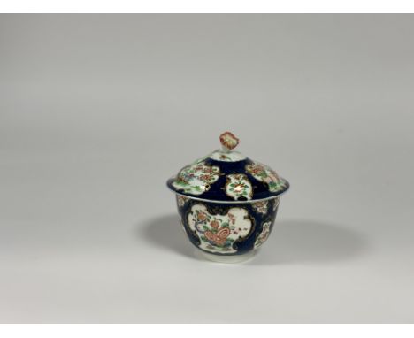 A Worcester porcelain sucrier and cover, c. 1775, painted in Kakiemon style with the Rich Queen's pattern in panels on a blue