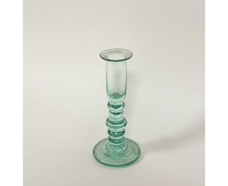 A late 18th / early 19th century glass candlestick, with elongated cylindrical cup on a knopped bobbin baluster stem and slig