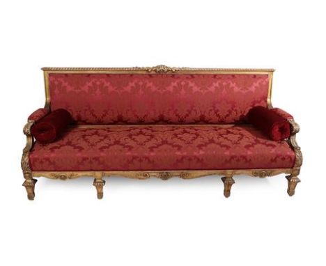 A French Carved Giltwood Sofa, late 19th century, in Louis XIV style, recovered in red and floral patterned damask, the mould