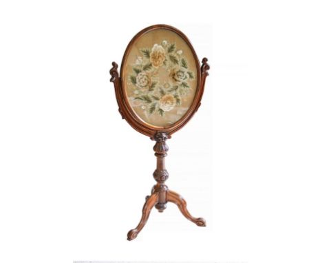 An early Victorian carved rosewood firescreen, the oval screen with original silk and velvet floral panel raised on a lappet 