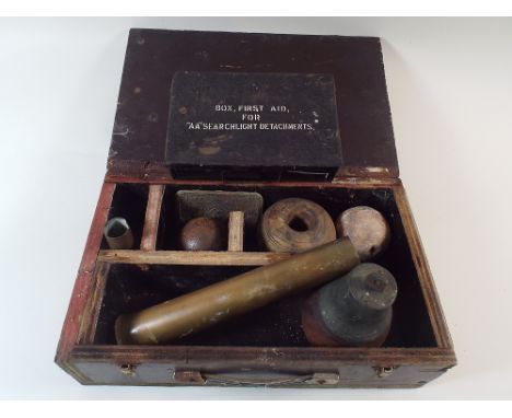 A Box Containing Military Curios to Include Cannon Ball, Brass 1956 Shell Case, Hand Bell, First Aid Box for Search Light Det