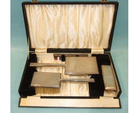 An engine-turned silver dressing table set of oblong design, mirror, hair brush, clothes brush and comb frame, in fitted case