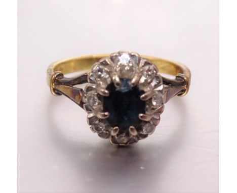 A sapphire and diamond cluster ring set eight brilliant-cut diamonds around an oval sapphire, in 18ct gold mount, size M, 4.2