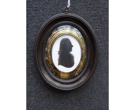 An 18th century oval silhouette portrait on plaster, William Williams, under convex verre eglomise glass within ebonised fram