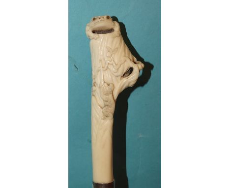 A finely-carved Japanese ivory walking stick handle, with a monkey climbing a rock and a toad with inlaid mother-of-pearl eye