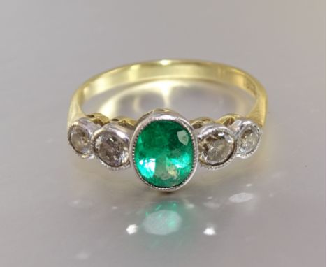 An Edwardian emerald and diamond ring collet-set an oval emerald of approximately 0.9cts, between two pairs of brilliant-cut 