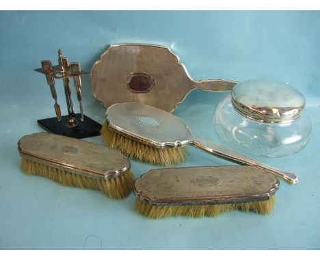 A four-piece silver engine-turned dressing table set, London 1940/1, a three-piece manicure set, (missing one piece) on stand