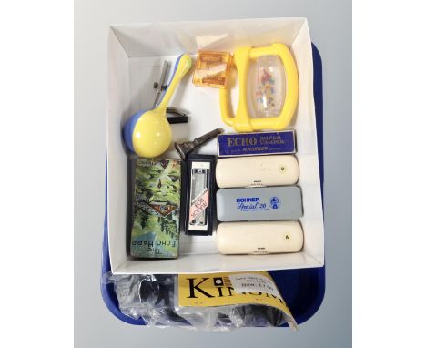 A tray containing assorted mouth organs including Hohner and Suzuki examples, a musical instrument mouthpiece and a new guita