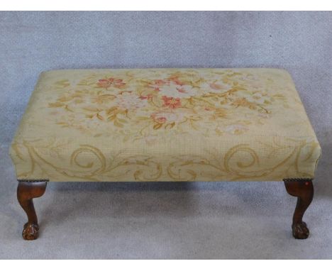 A large tapestry upholstered footstool on beech ball and claw carved cabriole supports. H.34 W.100 D.64 