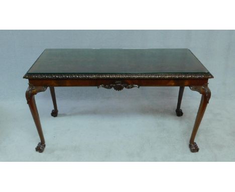 A Georgian style flame mahogany console table with plate glass top above carved frieze on cabriole supports terminating in ba