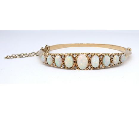 An antique yellow gold open diamond half snap hinged set bangle, possibly 15/18ct gold, set with nine graduated white cabocho
