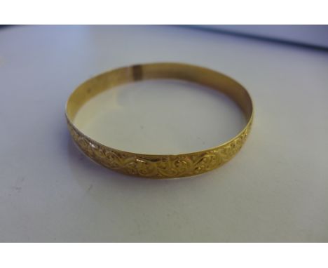 A yellow gold bangle with impressed marks, 6.5cm diameter, approx 22 grams, with scroll decoration, generally good, tests abo