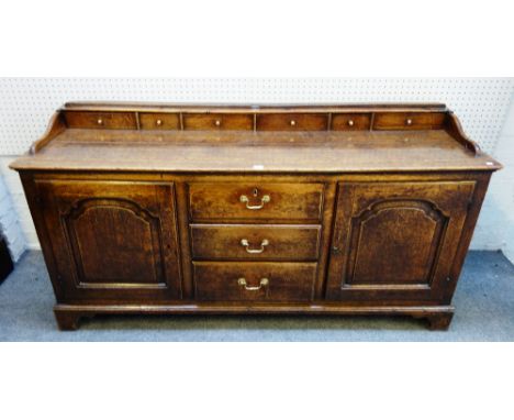 An 18th century oak dresser base, the plate rack with six spice drawers over three drawers flanked by cupboards, 170cm wide x