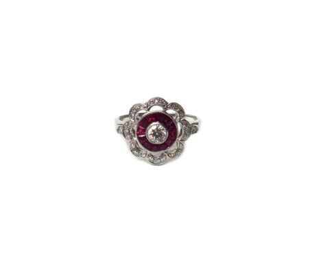 A white gold, diamond and ruby set shaped circular cluster ring, collet set with the principal circular cut diamond at the ce