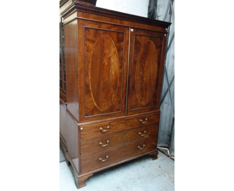 A George III mahogany linen press, the pair of oval inlaid doors over three long drawers on ogee bracket feet, 126cm wide x 1