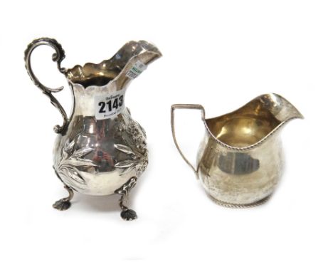 A Victorian silver milk jug, with floral embossed decoration, scrolling handle and raised on three shell capped pad feet, Lon