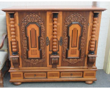 A 19th century German oak and fruitwood side cabinet, with pair of doors over drawers applied with leaf carving and split bob