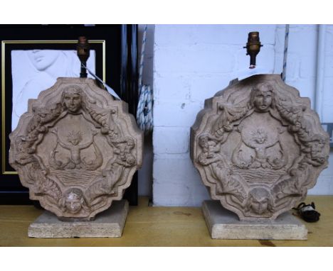 A pair of shaped and carved stone table lamps (formerly architectural embelishments), each decorated with figures and mytholo