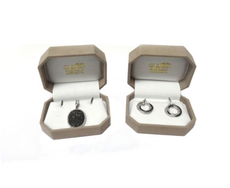 A white gold, black diamond and diamond set oval pendant, pave set with circular cut black diamonds to the centre, within a s