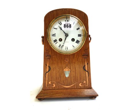 An oak Arts and Crafts mantel clock, with copper and mother-of-pearl inlay, the twin handles flanking an enamelled dial detai