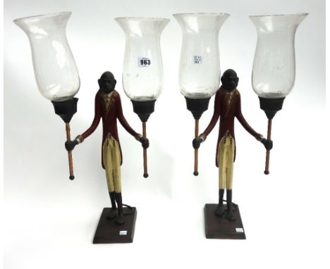 A pair of modern polychrome painted metal two branch candelabra, modelled as a suited monkey, each holding a torch with glass