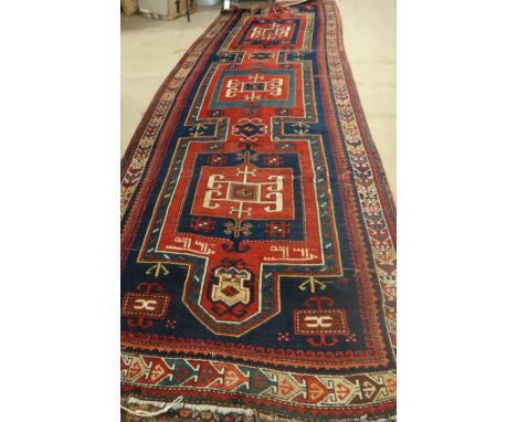 A Kazak runner, Caucasian, the dark indigo field with three bold connecting squares, an arrow border, dated 1335, 468cm x 160