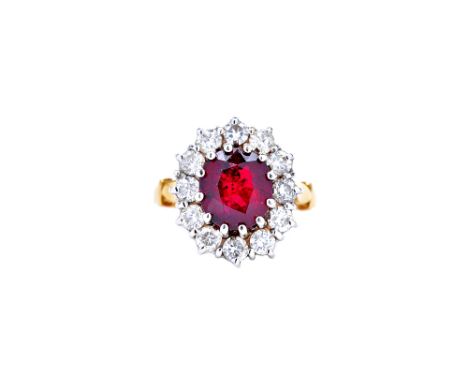 An 18ct gold, ruby and diamond oval cluster ring, claw set with the oval cut ruby at the centre, in a surround of twelve circ