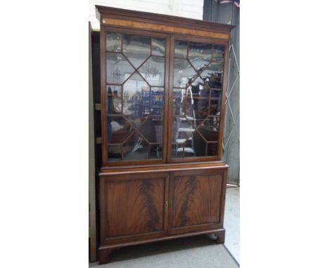 A George III mahogany and satinwood bookcase, with a pair of astragal glazed doors over panelled lower doors, on bracket feet