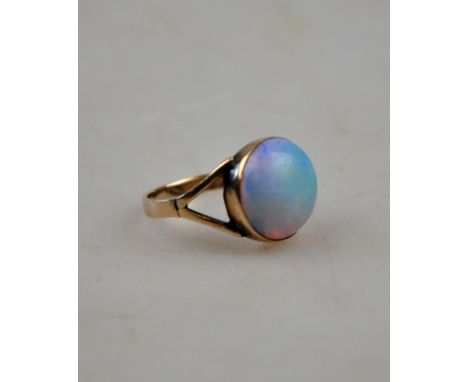 A single stone circular opal cabochon yellow metal set with closed back and open shoulders a/f