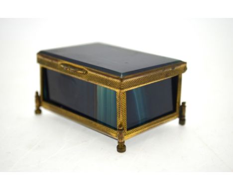 A rectangular blue banded dyed agate box with hinged lid, having gilt metal engine-turned mounts with four adjustable feet, 6
