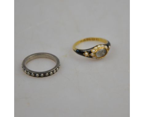 A Victorian yellow gold mourning ring, with black enamelled shoulders each set with seed pearl, and with central oval bezel e