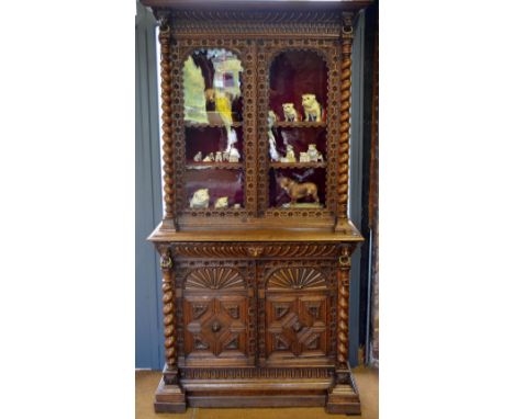 A Victorian carved and jointed oak library bookcase having a pair of arch-glazed doors enclosing adjustable shelves over a fu