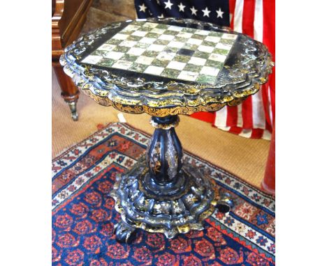 A Victorian mother-of-pearl and gilt decorated papier mache games table, the shaped circular tilting top inlaid with chess bo