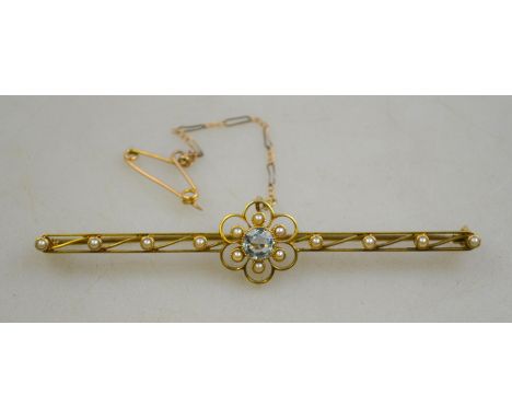 An unmarked yellow metal bar brooch, set with an aquamarine in foliate surround, flanked by seed pearls, 7.5 cm wide