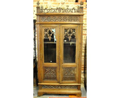 A 19th century French oak Gothic Revival library bookcase/cabinet, the fret cut and finial galleried top with glazed panel do